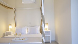 Ein ordentlich eingerichtetes Schlafzimmer mit einem Himmelbett, Nachttischen mit Lampen und einem Tablett mit Gläsern und Snacks.