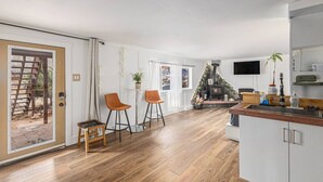 Eine moderne Küche mit Einbauherd, Holzboden und einer Essecke mit zwei Stühlen.