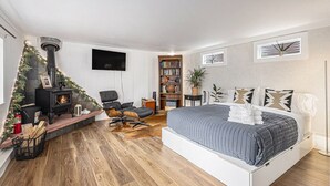 Ein modernes Schlafzimmer mit einem großen Bett, einem Kamin, einem Bücherregal und einem Fernseher.