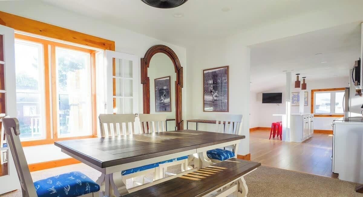 A spacious living area with a dining table, chairs, and a kitchen in the background.