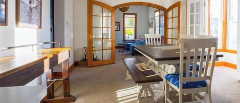 A dining area with a wooden table and chairs, a bench, and a view through an arched doorway.