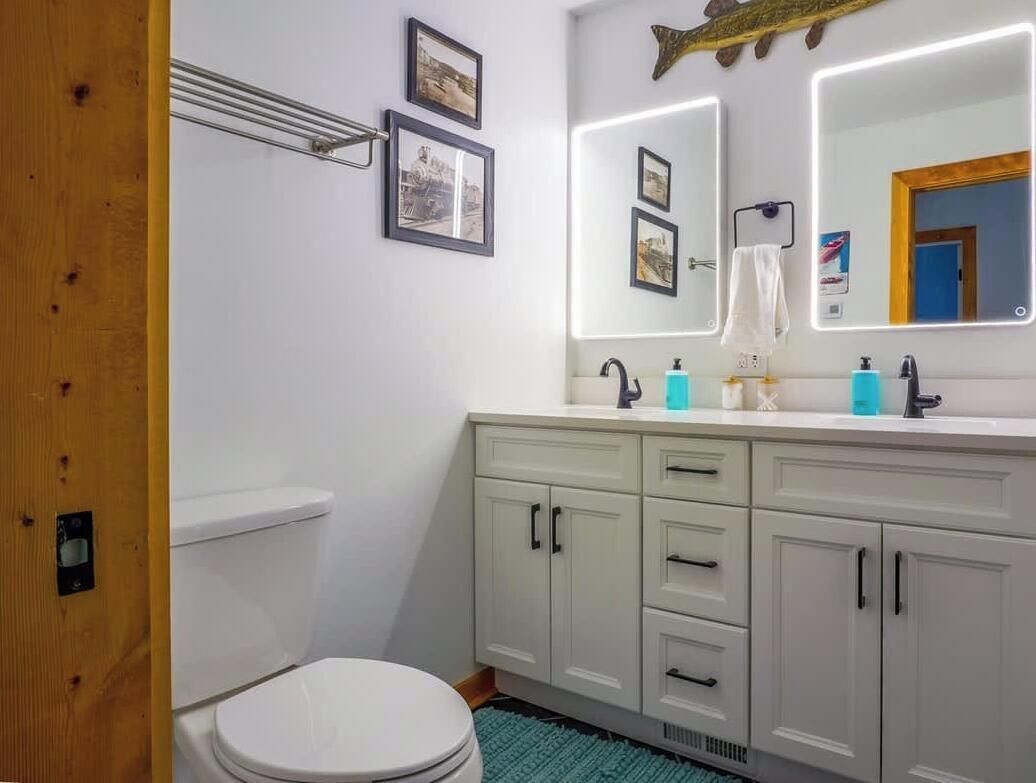 A bathroom with a toilet, a sink with a mirror, and cabinets.