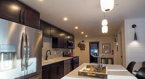 A modern kitchen with stainless steel appliances, dark cabinetry, and a central island with a wire basket.