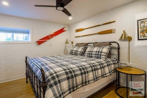 Une chambre à coucher comprenant un lit, un ventilateur de plafond, une fenêtre et des éléments fixés au mur.