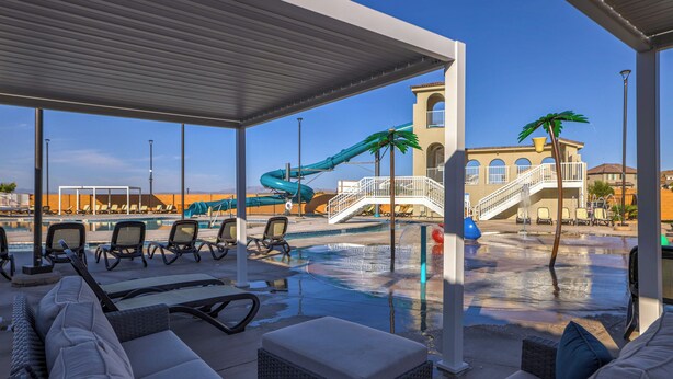 Ein Poolbereich mit Liegestühlen, einer Wasserrutsche und einer Palme.