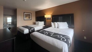 Una habitación de hotel con dos camas, un escritorio y un espejo.