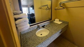 Un baño con encimera de granito, un lavabo, un espejo y un perchero para toallas.