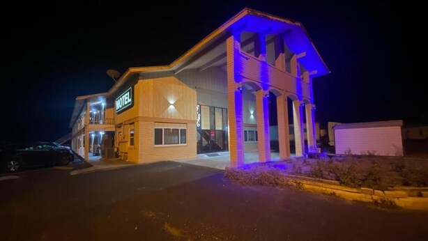Un motel con un letrero, un estacionamiento y un edificio con arcos.