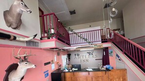 Un hall de hotel con mostrador de recepción, una escalera y cuernos de animales montados en las paredes.