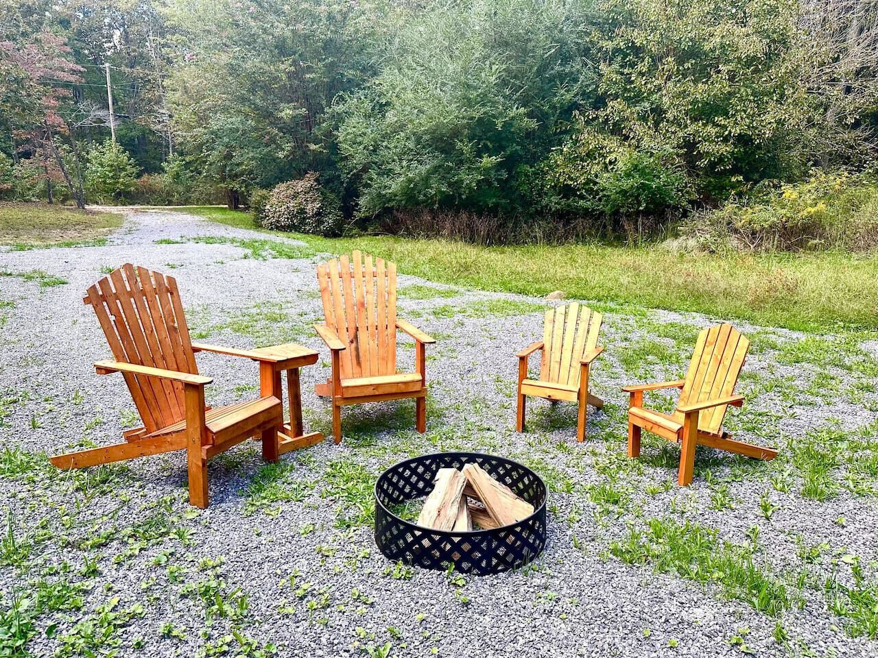 Ett område med grus, fyra trästolar i Adirondack-stil och en rund eldstad.