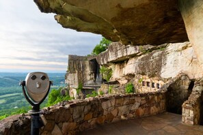 A stone viewing platform with a telescope, overlooking a lush valley and a historic stone structure. - Daffodil Hill • Walk to Downtown & Brow Park (Mentone)