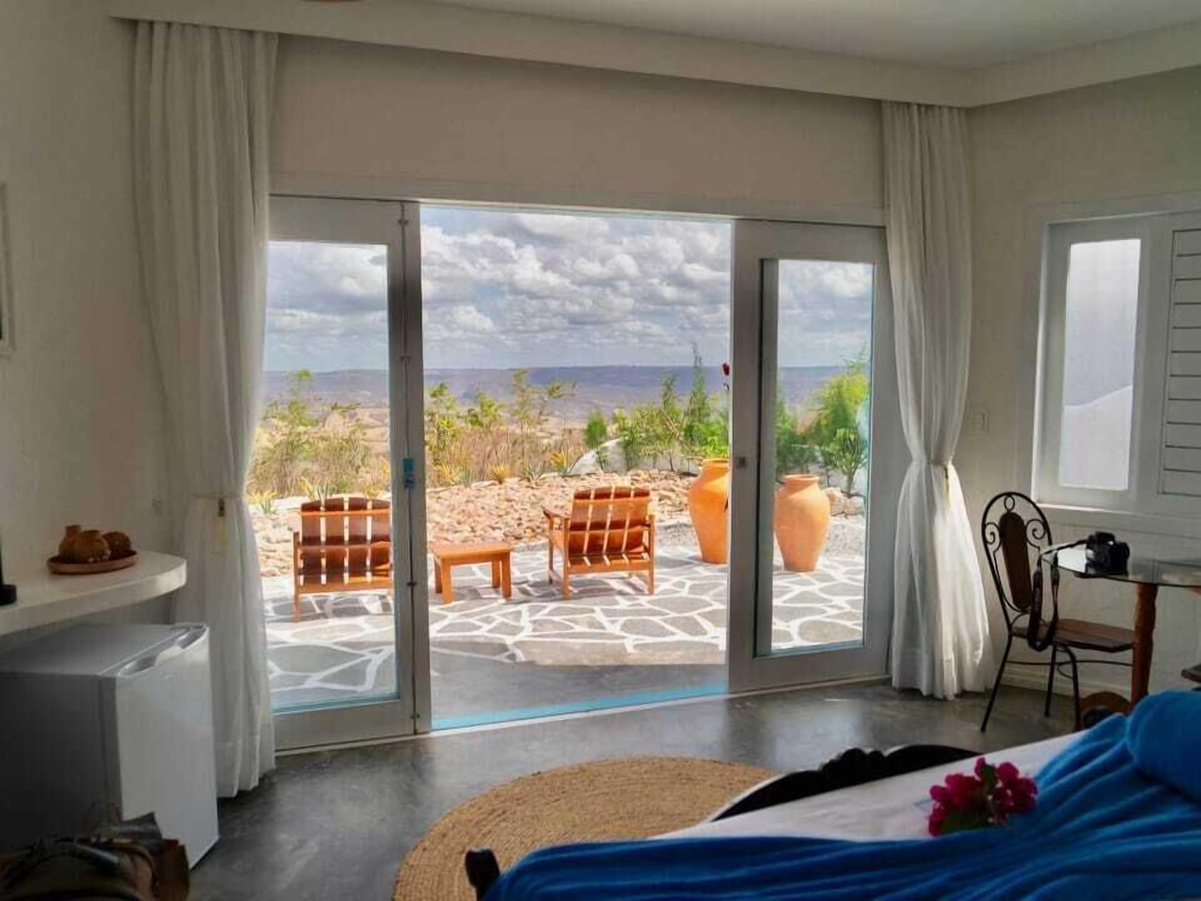 Un dormitorio con un amplio ventanal corredero que da a un espacio exterior con vistas al paisaje.