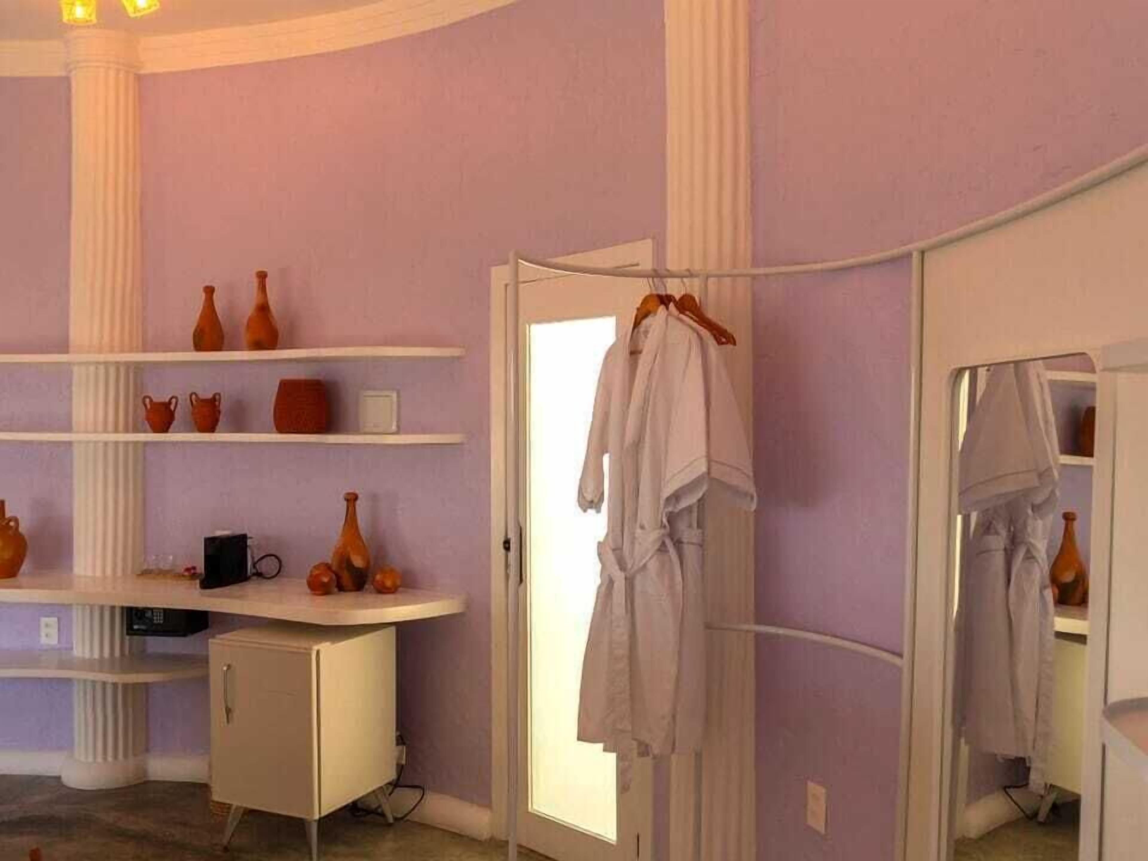 A bathroom with a vanity, a mirror, and a robe hanging on a rack.