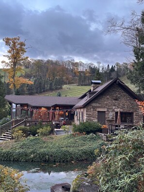 A stone building with a sloped roof and a porch area with outdoor seating. - Cozy Mountain Retreat- ski-in / ski-out townhouse at 7-Springs Ski Resort (Champion)