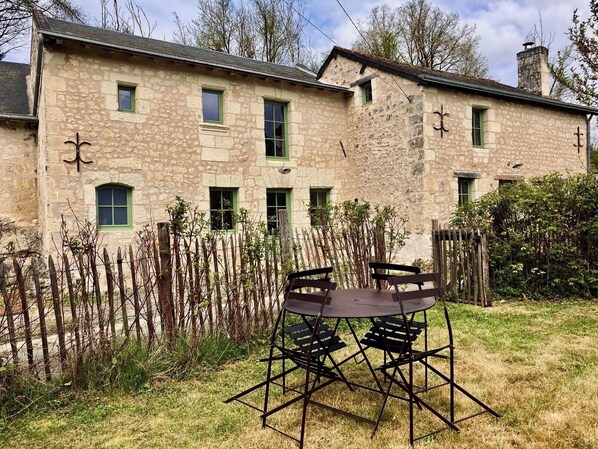 Un bâtiment en pierre doté de nombreuses fenêtres et d’un jardin clos.