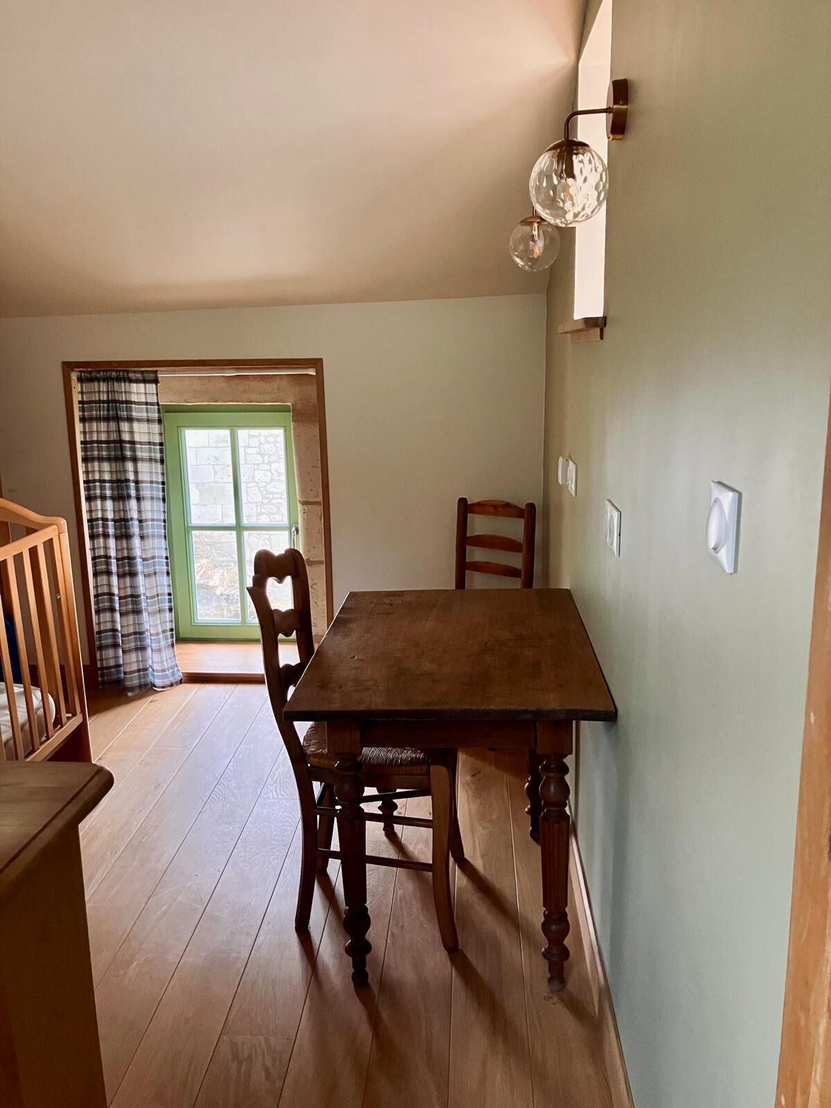 A dining area with a wooden table and chairs, a window with a view, and a staircase leading to another level.