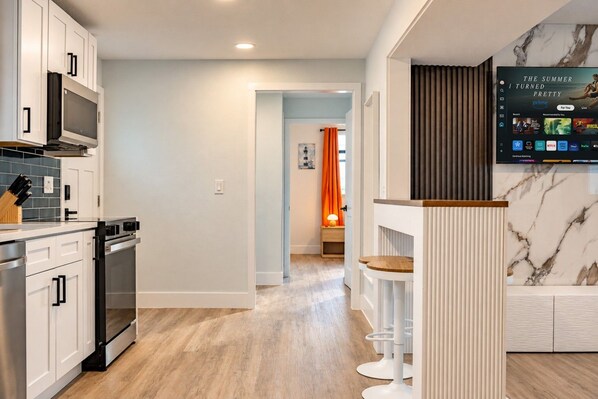 A modern kitchen with white cabinetry, a built-in microwave, and a wooden countertop. - Clearwater Bliss Apartments 3 (Clearwater)