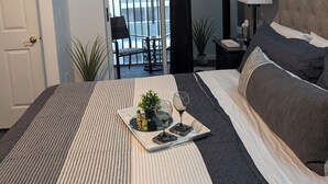 Une chambre avec un lit, une table de chevet, une lampe et une vue sur le balcon.