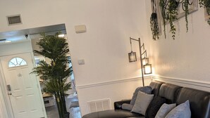 Un salon moderne avec un canapé en cuir noir, une table basse en verre et une plante en pot.