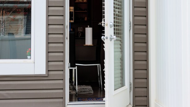 Une entrée de maison avec une porte-fenêtre coulissante, un petit porche et un intérieur visible, avec un escalier.
