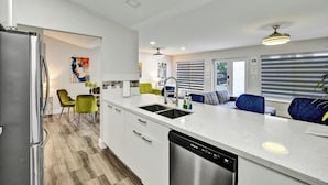 Una cocina moderna con lavavajillas integrado, un lavabo y una zona de comedor con sillas.