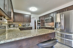 A modern kitchen with granite countertops, stainless steel appliances, and dark wooden cabinets. - Spacious Resort-Style Escape in Oklahoma City (Oklahoma City)