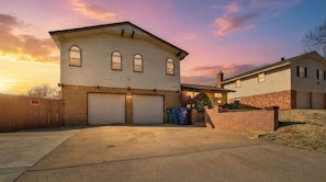 A two-story house with a garage, a fenced yard, and a brick wall. - Spacious Resort-Style Escape in Oklahoma City (Oklahoma City)