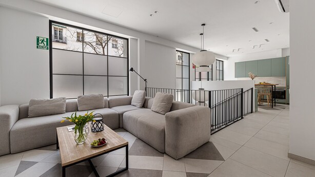 Een moderne woonkamer met een hoekbank, een houten salontafel en een groot raam.