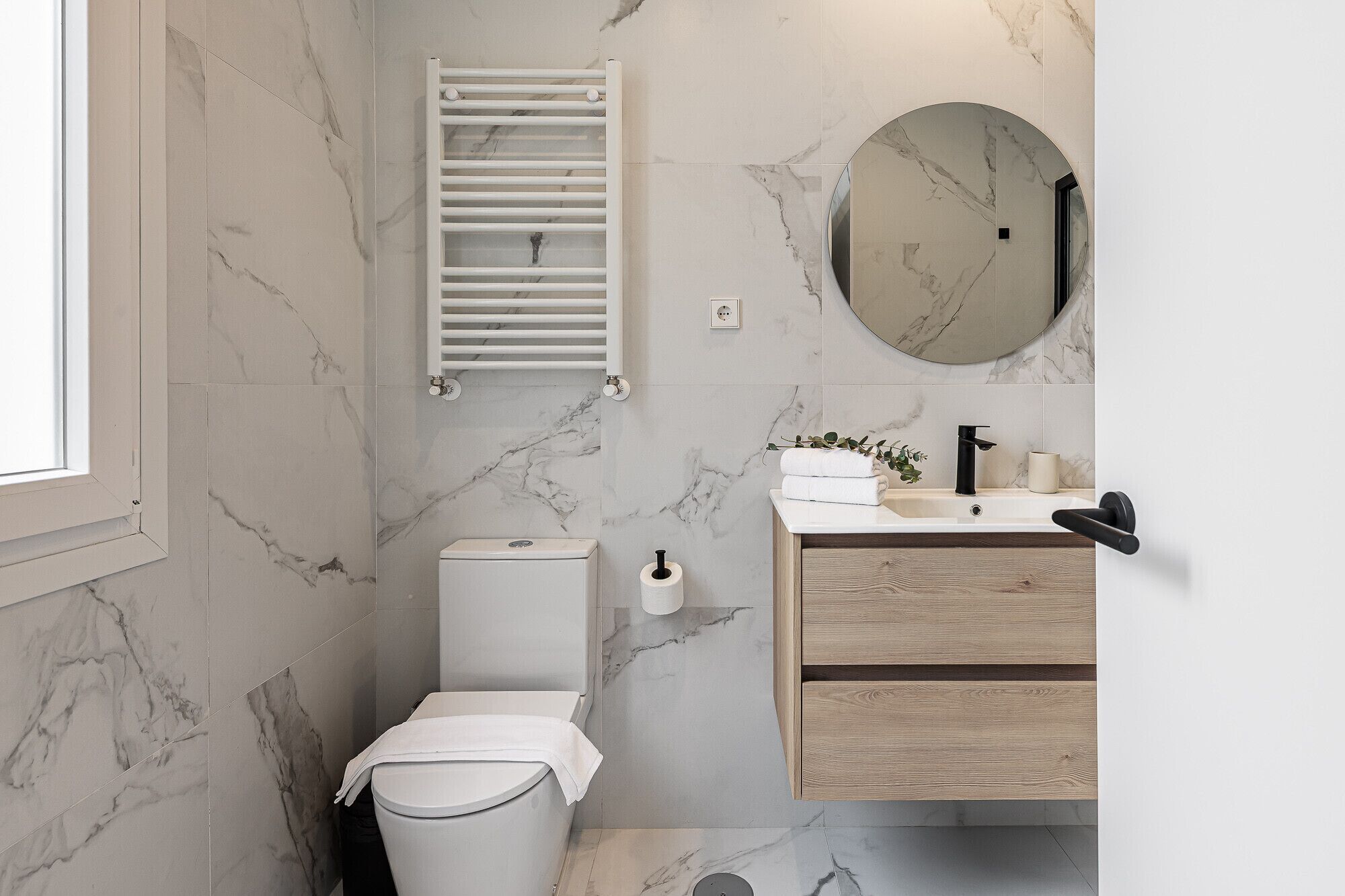 Un baño moderno con inodoro, lavabo y espejo.
