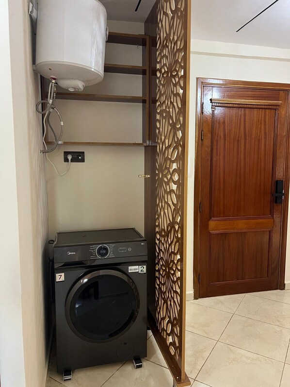 A laundry room with a washing machine, a water heater, and a wooden door.