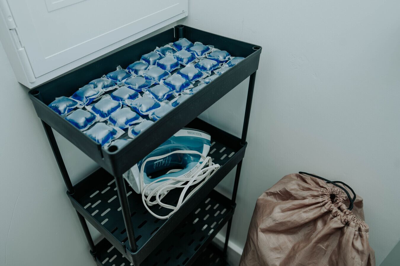 A metal shelf with blue and white bags, a face mask, and a bag of trash.