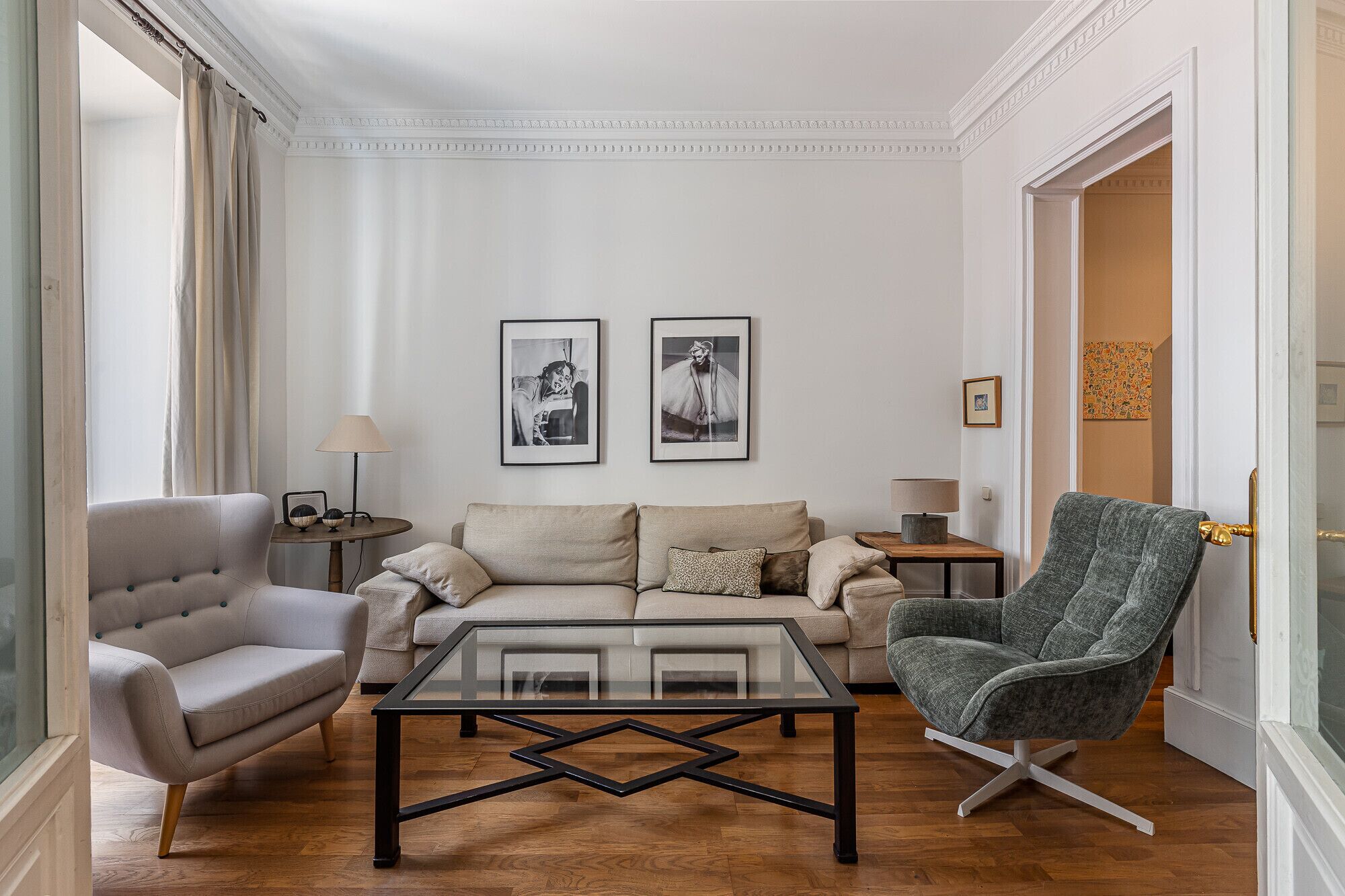 Un salon comprenant un canapé, un fauteuil et une table basse, une lampe, ainsi que deux tableaux encadrés accrochés au mur.