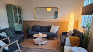 A modern living room with a dark grey sofa, a round coffee table, and a green cabinet.
