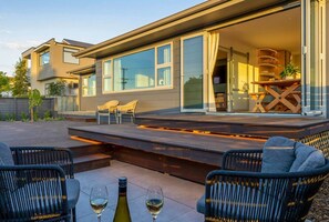 Una casa moderna con un patio amueblado con asientos exteriores y una botella de vino.