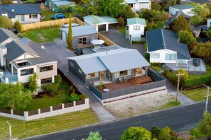 Un área residencial moderna con casas independientes, una casa central con porche cubierto y un césped bien cuidado.