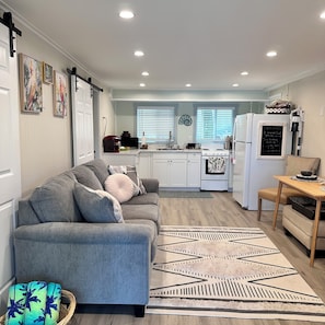 A compact living space with a sofa, a dining table, a kitchen area, and a decorative wall piece. - Waterfront "Pelican's Paradise Retreat"
Tybee bear kept secret! (Tybee Island)