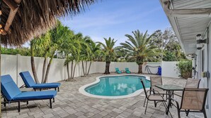 Um quintal com piscina, espreguiçadeiras e uma mesa.