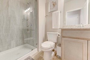 A bathroom with a glass-enclosed shower, a toilet, and a vanity with a mirror. - Charming Troy Escape Comfort Near Waco (Troy)