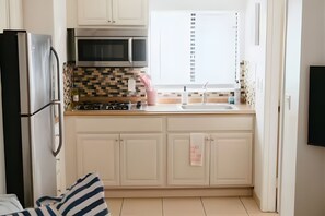 Eine kleine Küche mit Kühlschrank, Mikrowelle, Herd und Spüle.