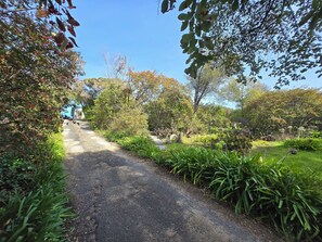 A paved pathway flanked by lush greenery and trees. - Holiday House - 500m to the beach (Rye)