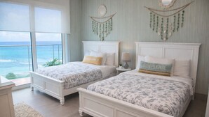 Ein Schlafzimmer mit zwei Betten, Meerblick und einem Balkon.