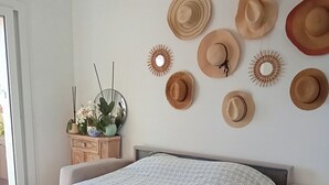 A bedroom with a bed, a dresser, a mirror, and a wall decorated with hats. - Sea-view terrace. 2mn from the streetcar, very well equipped, Pets welcome (Nice)