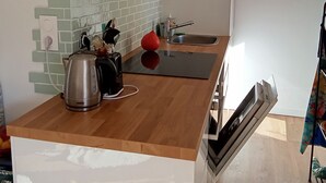 A modern kitchen with a wooden countertop, a stainless steel kettle, a red apple, and a built-in dishwasher. - Sea-view terrace. 2mn from the streetcar, very well equipped, Pets welcome (Nice)