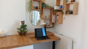 A wooden desk with a laptop, a mirror, and shelves with books and plants. - Sea-view terrace. 2mn from the streetcar, very well equipped, Pets welcome (Nice)