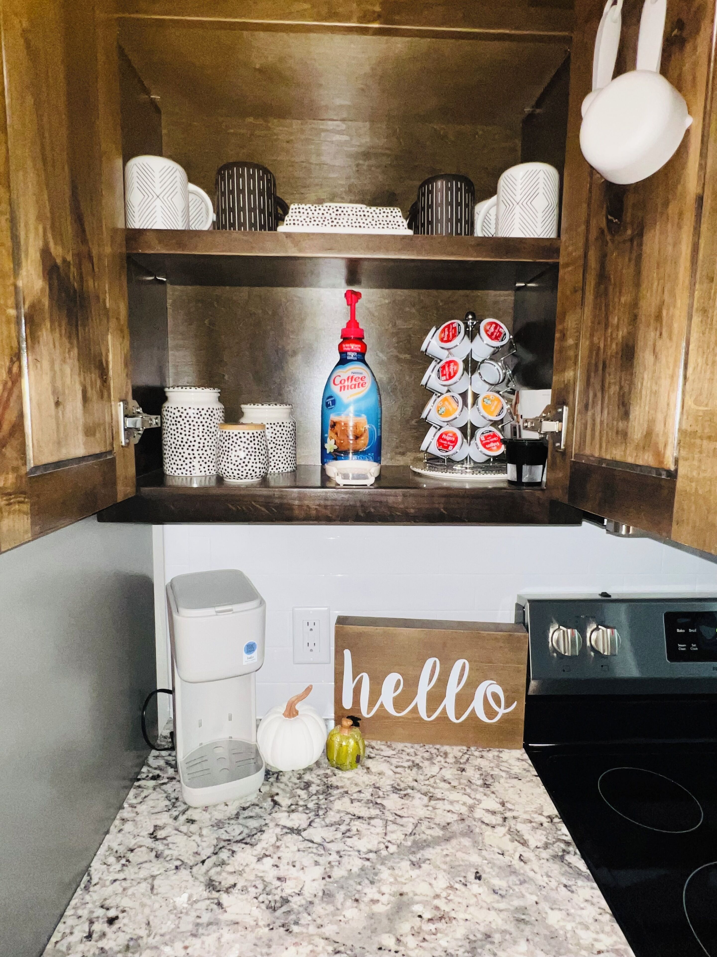 Una cucina con una macchina per il caffè, un distributore di caffè, una moka e un cartello con la scritta 'hello' sul bancone.