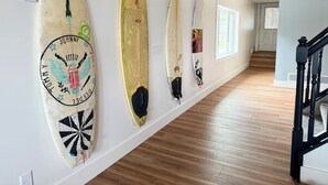 A hallway with surfboards mounted on the wall, wooden flooring, and a staircase. - HAVEN COTTAGE - Close to Mpls, Far From Your Routine-FREE SUPS on Lake Fremont! (Zimmerman)