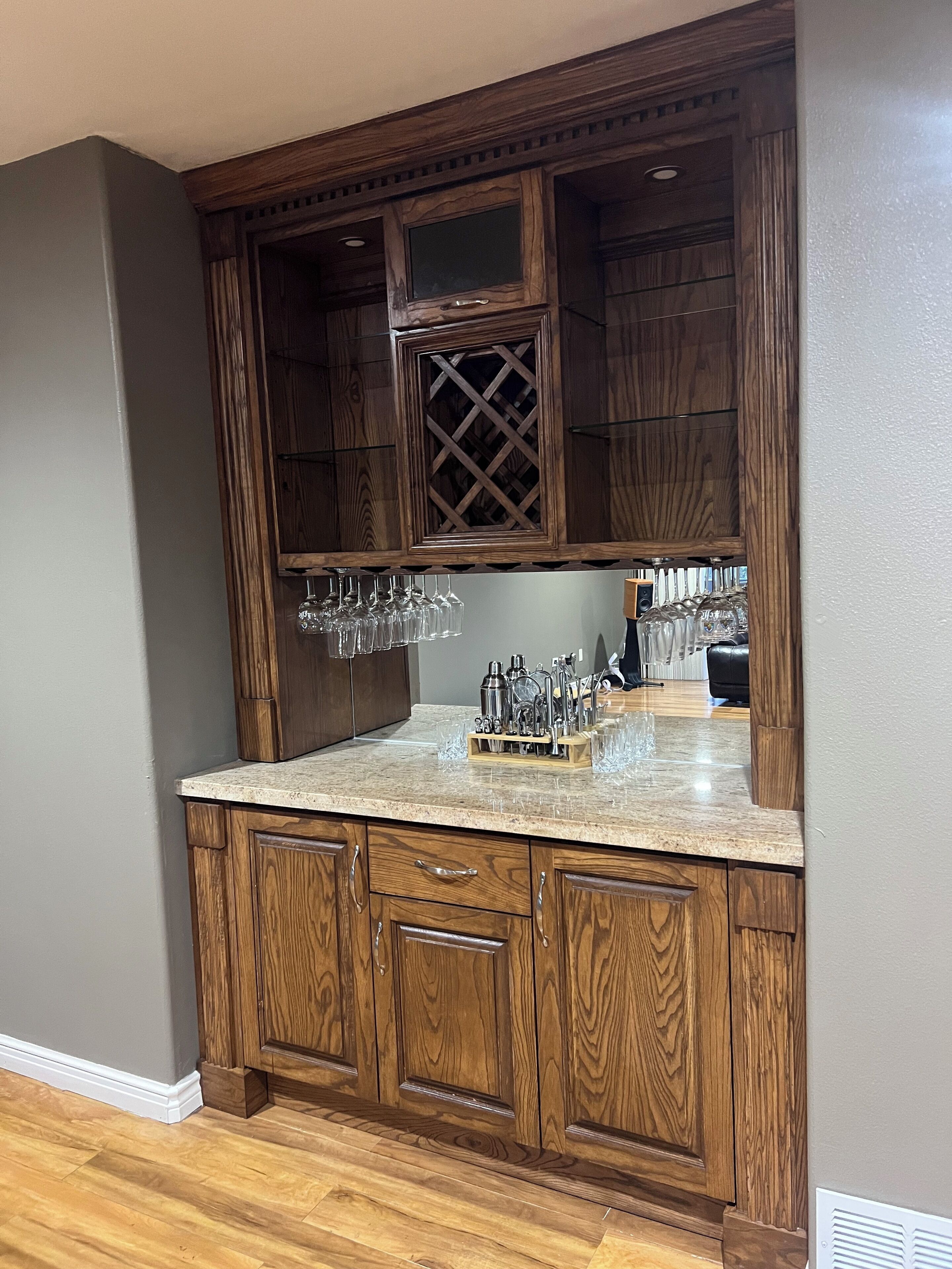 Una cocina con armarios de madera, encimera de granito y una estantería para vinos con copas.