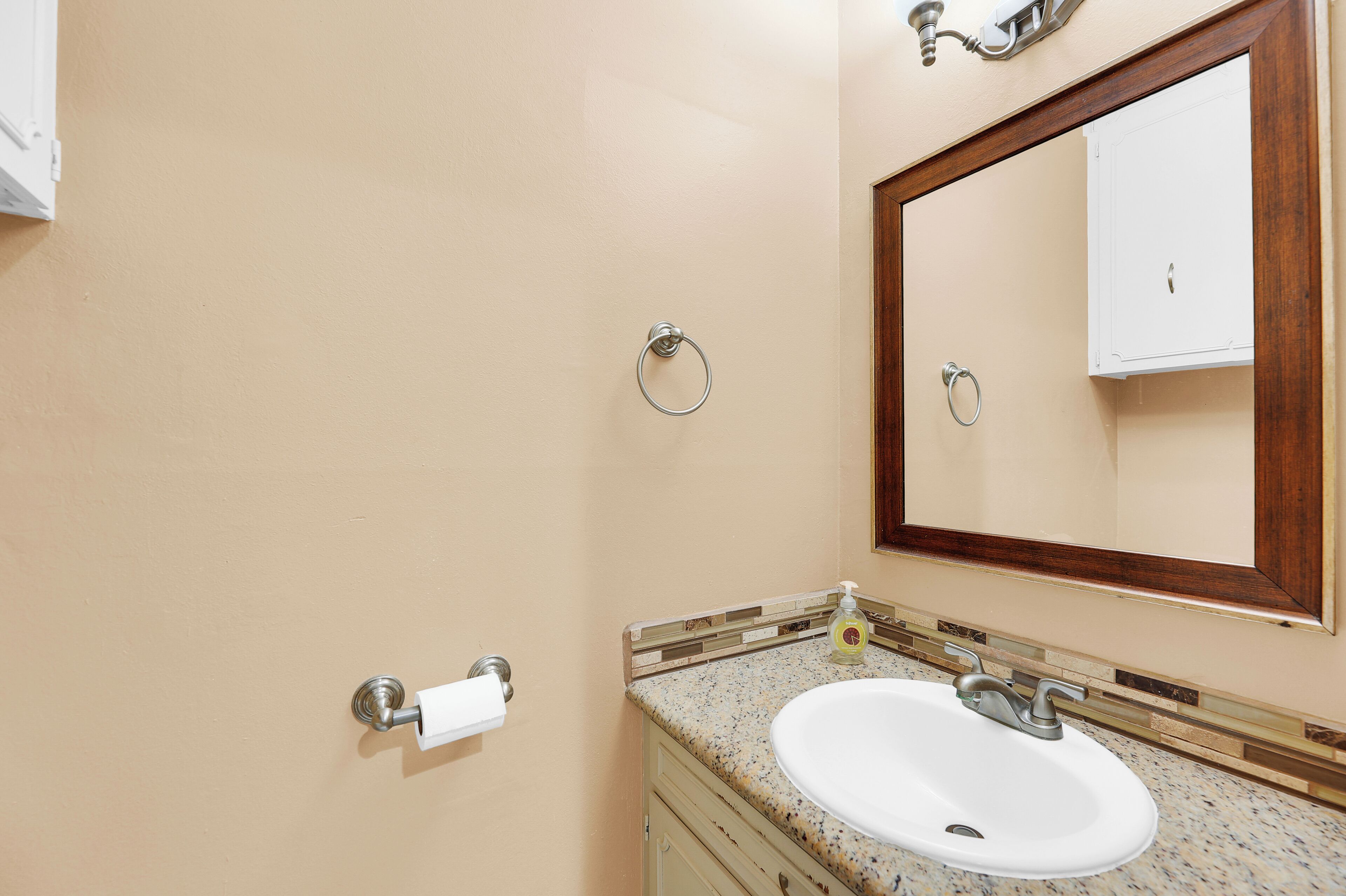 A bathroom with a white sink, a mirror, and a towel dispenser.