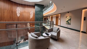 Eine moderne Lobby mit geschwungenem Glasgeländer, komfortablen Sitzgelegenheiten und einem Marmorboden.