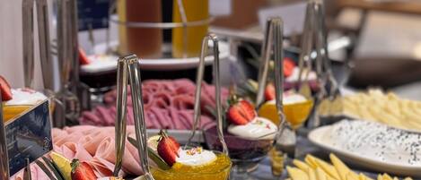 A buffet with various dishes and desserts, including a variety of fruits, cheeses, and a selection of bread.